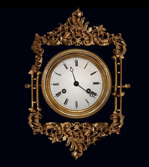 Old antique watch in a golden carved frame isolated on black.