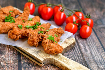
 Crispy  deep fried   chicken strips and wedges potato. Breaded  with cornflakes chicken  breast fillets  with chilly peppers and fresh   basil on wooden rustic background