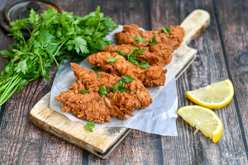 
 Crispy  deep fried   chicken strips and wedges potato. Breaded  with cornflakes chicken  breast fillets  with chilly peppers and fresh   basil on wooden rustic background