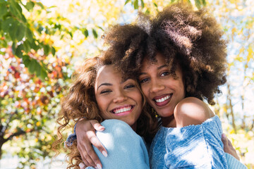 Closeup of two delighted happy female afro american friends hugging and smiling with love, giving warm hug and posing together. Truthful feelings, alternative love, mental health concept.