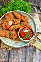 
 Crispy  deep fried   chicken strips and wedges potato. Breaded  with cornflakes chicken  breast fillets  with chilly peppers and fresh   basil on wooden rustic background