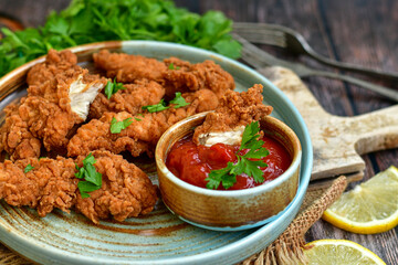 
 Crispy  deep fried   chicken strips and wedges potato. Breaded  with cornflakes chicken  breast fillets  with chilly peppers and fresh   basil on wooden rustic background