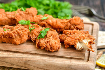 
 Crispy  deep fried   chicken strips and wedges potato. Breaded  with cornflakes chicken  breast fillets  with chilly peppers and fresh   basil on wooden rustic background