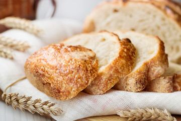 Close up of slices of freshly baked wheat bread on linen towel on wooden table, selective focus.