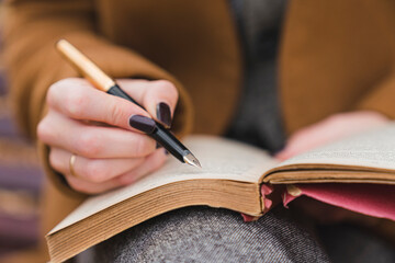 Woman with fountain pen writing in book in park