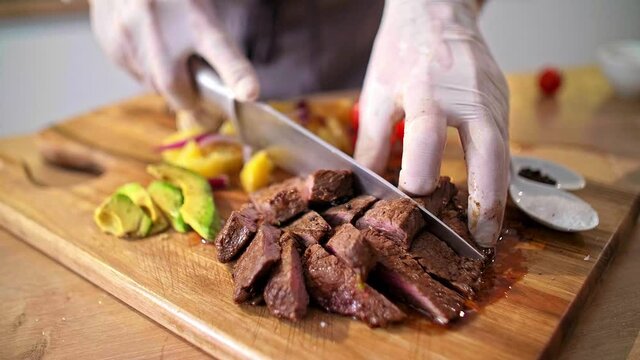 Close-up of chef cutting roasted meat on a wooden board