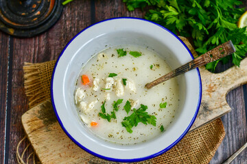 Home made chicken soup with noodles ,parsley and vegetables in white bowl . Healty soup