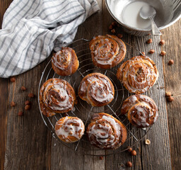 Cinnamon rolls with nuts and sugar icing on wooden table