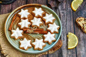 Gingerbread star shaped   cookies and cinnamon sticks    on   wooden background with lights . Christmas  card background  . Holiday wallpaper
