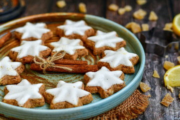 Gingerbread star shaped   cookies and cinnamon sticks    on   wooden background with lights . Christmas  card background  . Holiday wallpaper