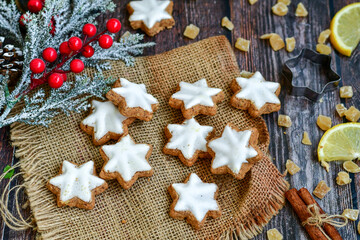 Gingerbread star shaped   cookies and cinnamon sticks    on   wooden background with lights . Christmas  card background  . Holiday wallpaper