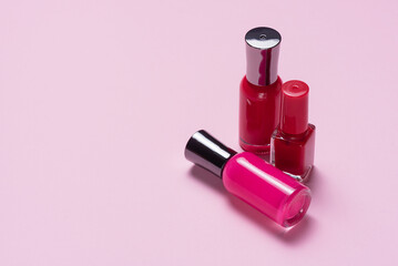 Nail polish bottles on the pink background close up with copy space.