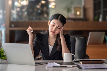 Beautiful young Asian businesswoman feeling tired from overworked.