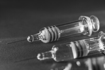 Close view of the glass syringes on a gray background. Medicine and health concept. Vaccine against viruses. Needle and drugs. Black and white