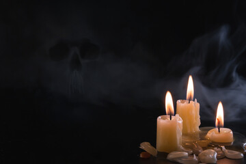 Candles isolated over dark background. Used, almost extinguished. Burned out. Copy space. Mystical smoke swirls in the dark, taking the shape of a skull. The concept of death and fear, dark magic