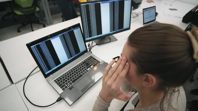 Nervous female programmer looking at her code on computer screen, trying to solve a code problem, bug
