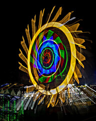 Fun fair Giant Colorful Ferris wheel spinning at night. Slow shutter zoom pan image of a rotating...