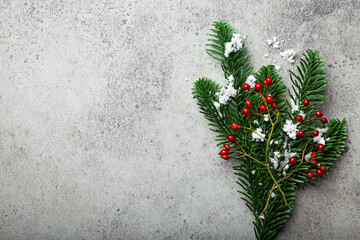 Christmas and New Year flat lay composition frame with green fir tree branch with snow and forest red berries on gray stone concrete background with free space for your text 