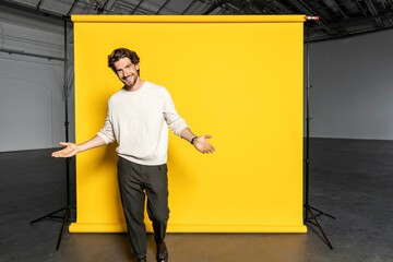 Handsome businessman gesturing in front of yellow backdrop