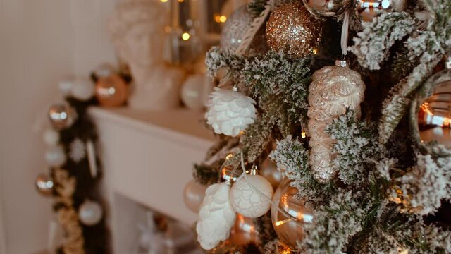 Decorated Christmas tree in the room. Coniferous tree with white and gild baubles located near the white wall during the celebration of the holiday