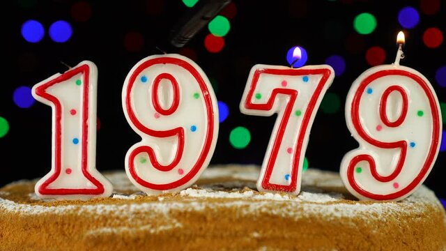 Birthday cake with white burning candles in the form of number 1979