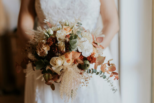 bride holding bouquet of autumnal flowers