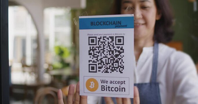 Asia people small SME owner stick QR code placard text label signage poster on glass virtual cash digital money service. Cryptocurrency Bitcoin ethereum blockchain logo on modern coffee cafe shop.  