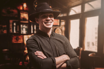 Portrait of a smiling man in a hat. Cowboy style. Saloon.