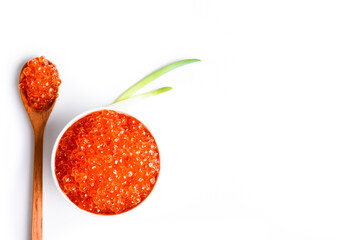 Red caviar in a wooden cup on a grey background with a spoon.