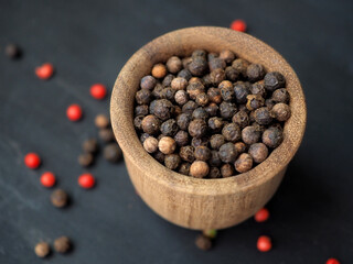 Jamaica pepper or  Allspice in a wooden bowl on a black background. Top view. Close-up