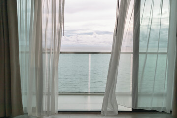 Almost evening time of ocean view from hotel balcony with curtains. © Sevendeman