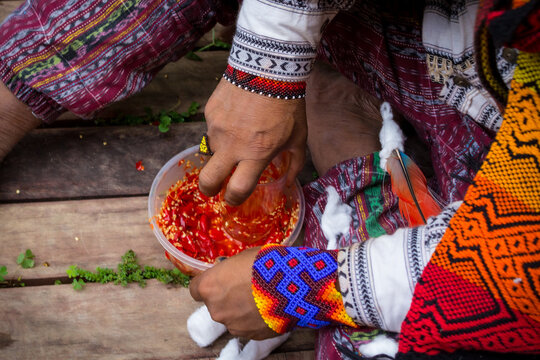 Sao Paulo, SP, Brazil - November 11 2021: Close-up of male hands with typical and colorful costumes and accessories macerating peppers details.