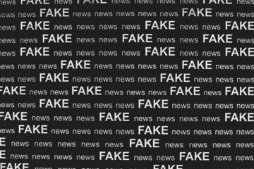 Text - FAKE news - printed on black sheet of paper