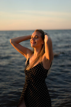 Smiling young woman with hands in hair at sunset