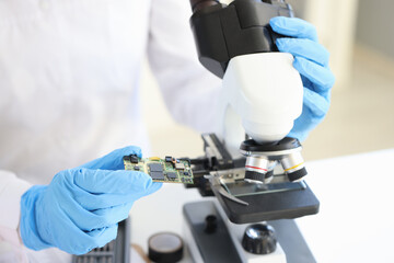 Scientist looking under microscope computer processor closeup