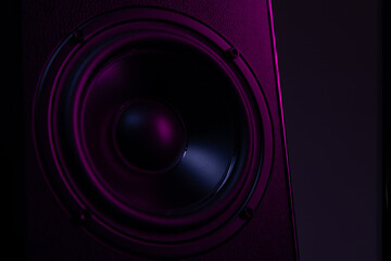 large speaker close-up on a black background with violet-purple illumination close-up, music...