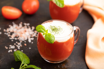 Tomato juice with basil and himalayan salt in glass on a black background. Side view, selective focus.