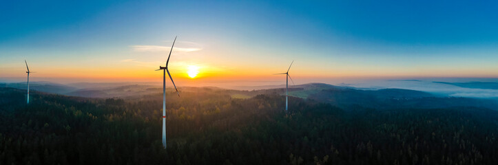 Aerial panorama of wind farm in forested Schurwald range at sunset