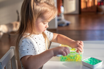 Little girl playing with sensory water beads, hydrogel balls. Sensory development and experiences,...