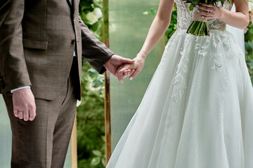 Happy bride and groom holding hands on wedding ceremony, copy space. Wedding couple in love,...