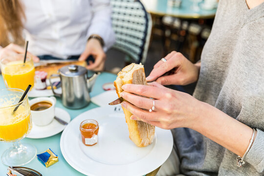 Young woman cutting baguette on plate at cafe