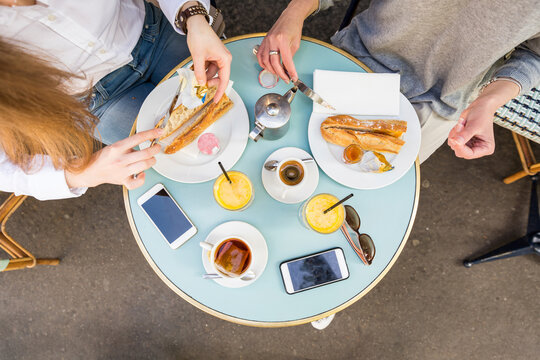 Friends applying butter on baguettes at table