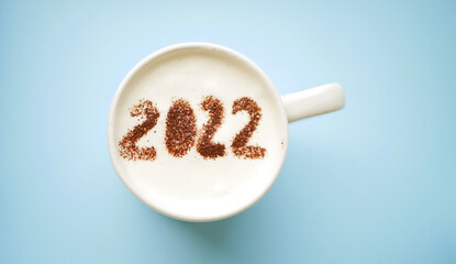 2022 year greeting in cup of coffee. Cocoa powder drawing on milk foam. Happy New Year