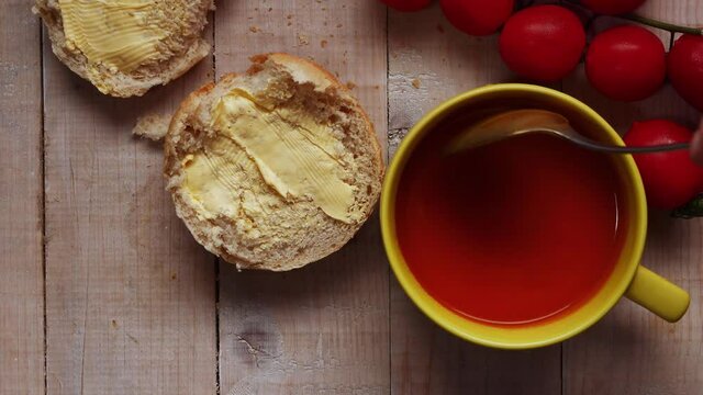 Stirring tomato soup with bread roll
