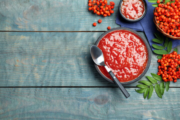 Flat lay composition with delicious rowan jam on light blue wooden table. Space for text