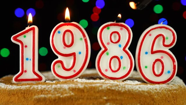 Birthday cake with white burning candles in the form of number 1986