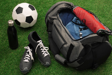 Gym bag and sports equipment on green grass