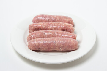Raw meat sausages on a white plate on a white plate. Homemade sausages in a natural casing. Meat products