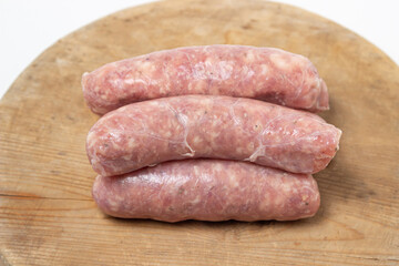 Raw meat sausages on a wooden board on a white background. Homemade sausages in a natural casing. Meat products