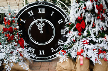 Close-up of festive decorations with Christmas tree, glass balls, garland, bokeh, clock. New Year tree on the city. New Years. Holiday concept. Winter celebrations.Countdown To Midnight. 